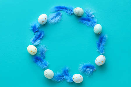 Frame made of beautiful Easter eggs and feathers on color backgroundの写真素材
