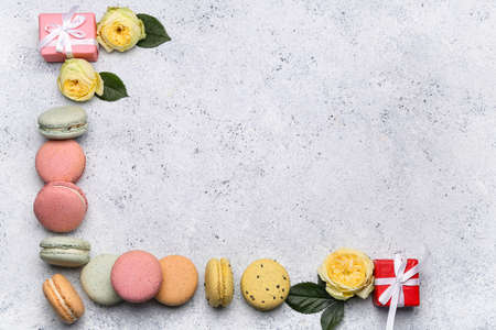 Composition with sweet macaroons, rose flowers and gifts for International Women's Day celebration on light backgroundの写真素材