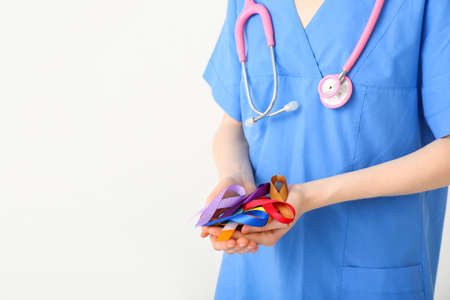 Female doctor holding awareness ribbons on white background. World Cancer Dayの写真素材