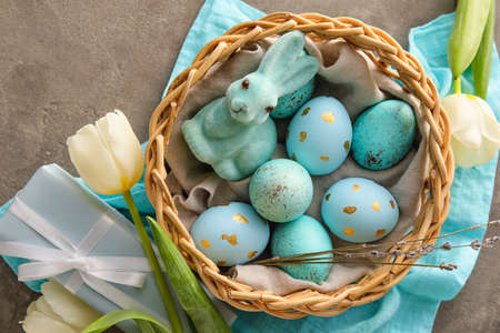 Basket with painted Easter eggs, bunny and tulip flowers on gray grunge backgroundの写真素材