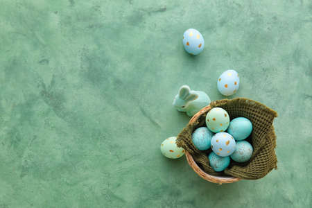 Basket with beautiful Easter eggs and bunny on green backgroundの写真素材