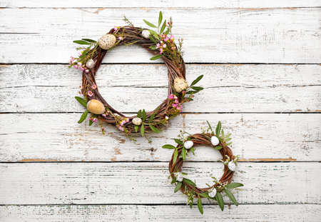 Easter wreathes with flowers, leaves and eggs on light wooden backgroundの写真素材
