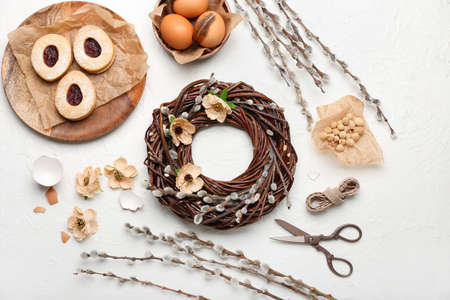 Composition with beautiful Easter wreath, pussy willow branches, eggs and cookies on light...