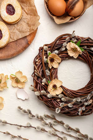 Composition with beautiful Easter wreath, pussy willow branches, eggs and cookies on light...