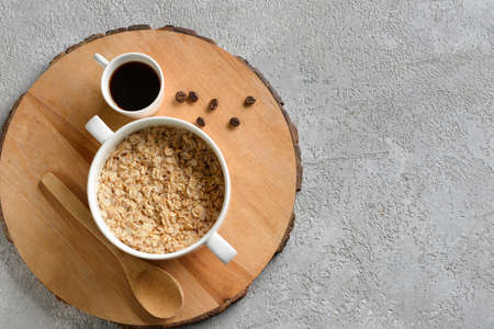 Pot of tasty oatmeal and cup with coffee on gray background