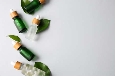 Composition with different bottles of serum and plant leaves on white backgroundの写真素材