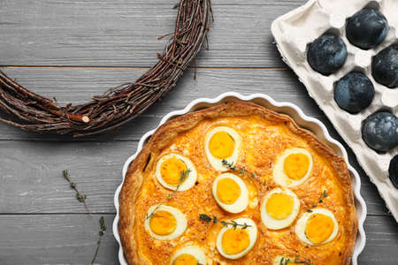 Tasty Easter tart, painted eggs and wreath on dark wooden backgroundの写真素材