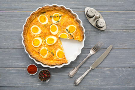 Tasty Easter tart with eggs, spices and cutlery on dark wooden backgroundの写真素材