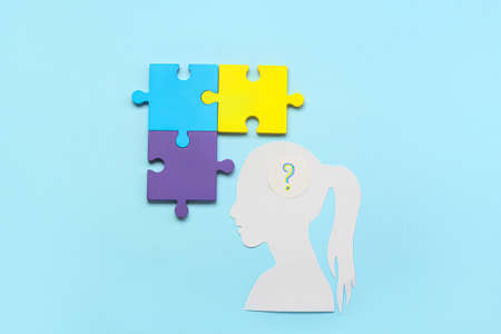 Paper female head with question mark and puzzle pieces on blue background. Concept of autistic disorderの写真素材