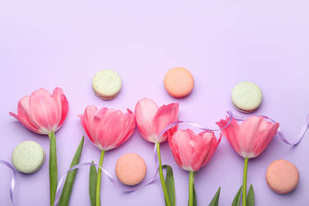 Beautiful tulip flowers and sweet macaroons on lilac background, closeup, International Women's Day celebrationの写真素材