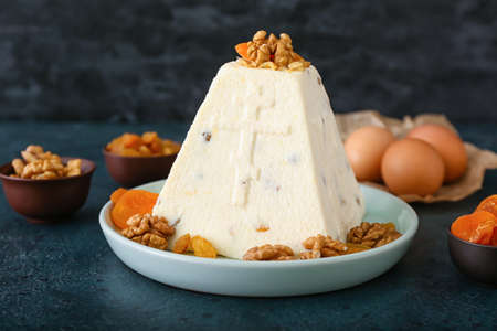 Plate with traditional curd Easter cake and walnuts on dark table