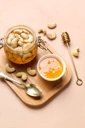 Jar of tasty cashew nuts with honey on beige backgroundの写真素材