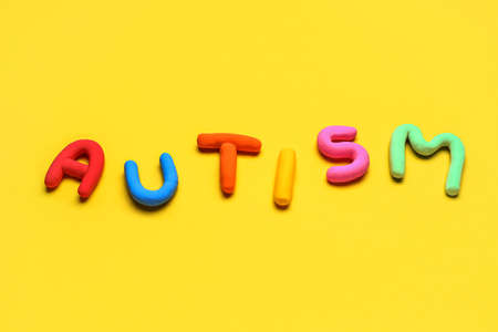 Colorful word AUTISM on yellow background