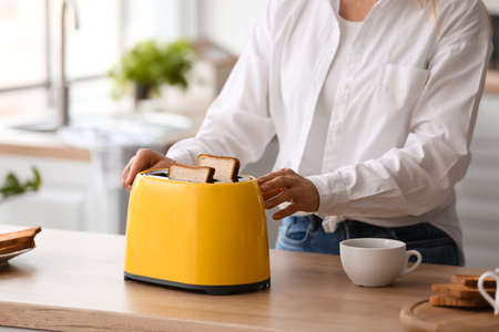 Mature woman making tasty toasts in the kitchen