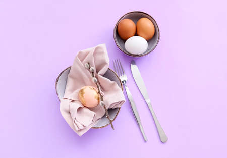 Beautiful table setting with Easter eggs and willow branch on lilac background