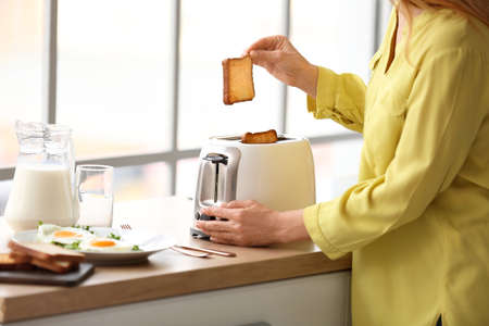 Mature woman making tasty toasts in the kitchenの写真素材