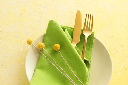 Beautiful table setting with flowers on yellow background