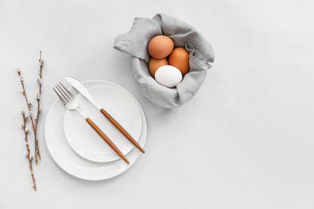 Beautiful table setting with Easter eggs and willow branches on light background