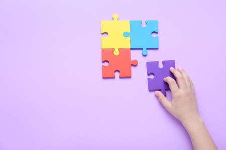 Child with puzzle pieces on lilac background. Concept of autistic disorderの写真素材