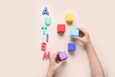 Child with cubes and word AUTISM on gray backgroundの写真素材