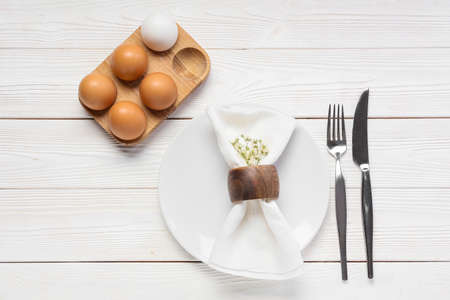 Beautiful table setting with Easter eggs and flowers on white wooden backgroundの写真素材
