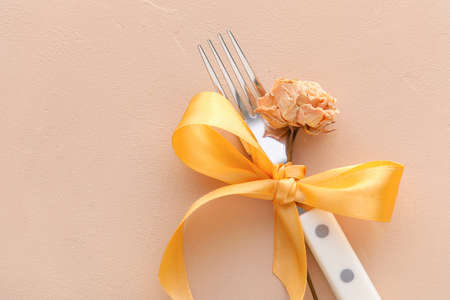 Fork with ribbon and flower on color backgroundの写真素材
