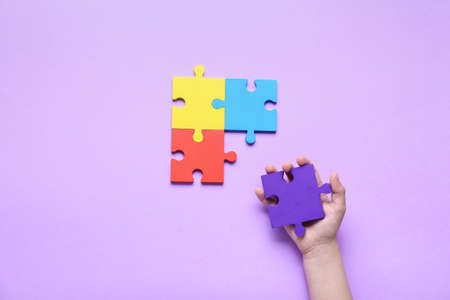 Child with puzzle pieces on lilac background. Concept of autistic disorderの写真素材