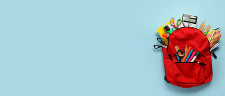 School backpack and stationery on light blue background with space for text