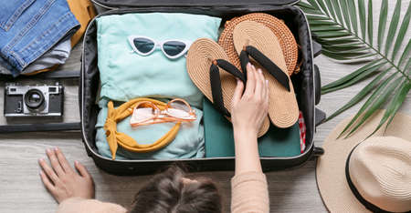 Young woman packing suitcase at home, top view. travel concept