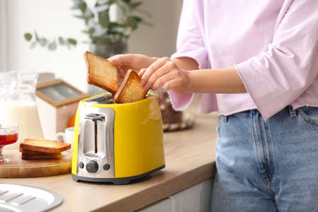 Beautiful young woman making tasty toasts in the kitchenの写真素材