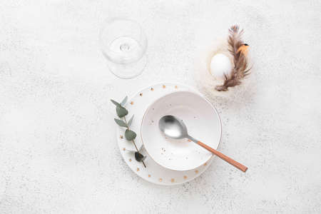 Beautiful table setting with Easter egg and eucalyptus branch on white background