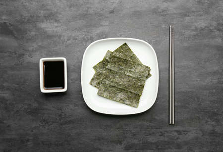 Plate of tasty seaweed sheets with soy sauce and chopsticks on black backgroundの写真素材