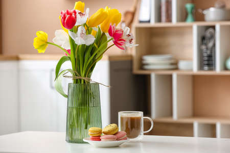 Vase with flowers and tasty breakfast on dining table in kitchenの写真素材