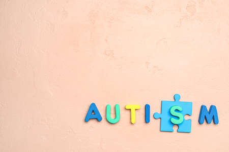 Word AUTISM with puzzle piece on gray background