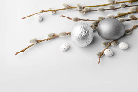 Easter eggs and pussy willow branches on light background
