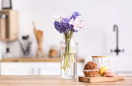 Delicious breakfast and vase with flowers on kitchen counter