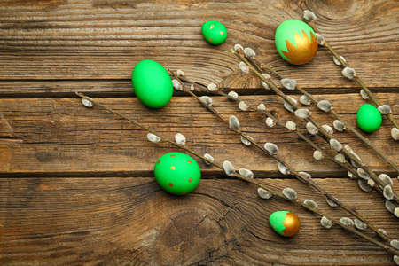 Painted Easter eggs and pussy willow branches on wooden background