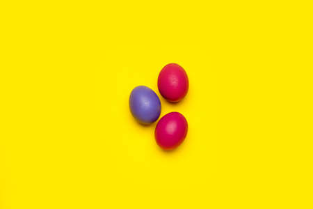 Three colorful Easter eggs on yellow background
