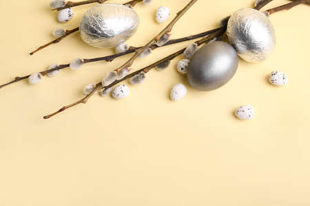 Easter eggs and pussy willow branches on color background