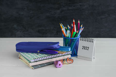 Different stationery on table near black wall