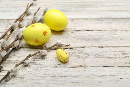 Painted Easter eggs and pussy willow branches on wooden background