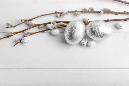 Easter eggs and pussy willow branches on light wooden background