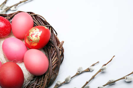 Nest with painted Easter eggs and pussy willow branches on light backgroundの写真素材