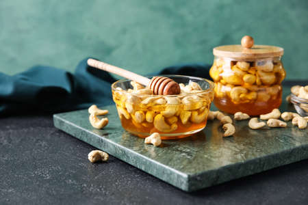 Board with sweet cashew nuts in honey on tableの写真素材