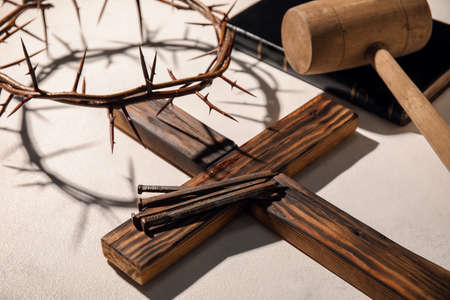 Cross with nails and crown of thorns on light background