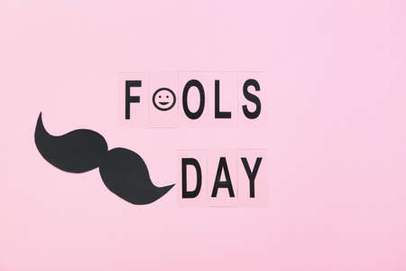 Composition with mustache and text FOOLS DAY on pink background