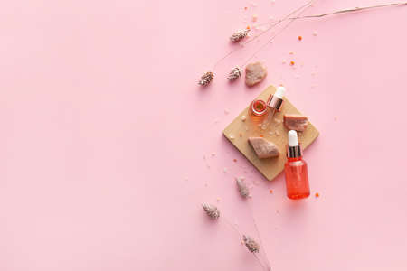 Bottles of natural serum, salt and flowers on pink backgroundの写真素材