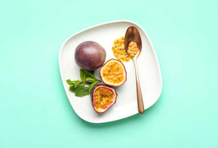 Plate with delicious passion fruit and spoon on green backgroundの写真素材