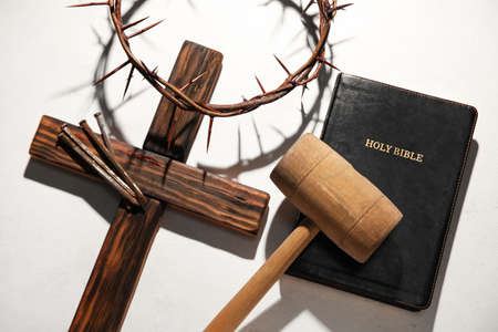 Crown of thorns with cross, mallet, nails and Holy Bible on light background