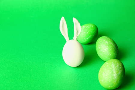 Creative composition with painted Easter eggs and rabbit ears on color backgroundの写真素材